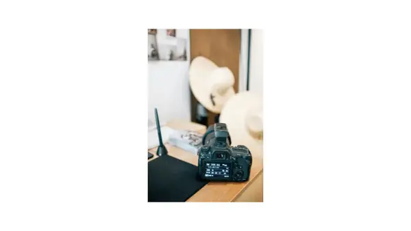 Aparat fotograficzny na biurku, obok kapelusze i tablet graficzny. To miejsce, gdzie zaczyna się nauka, jak zarabiać na zdjęciach.