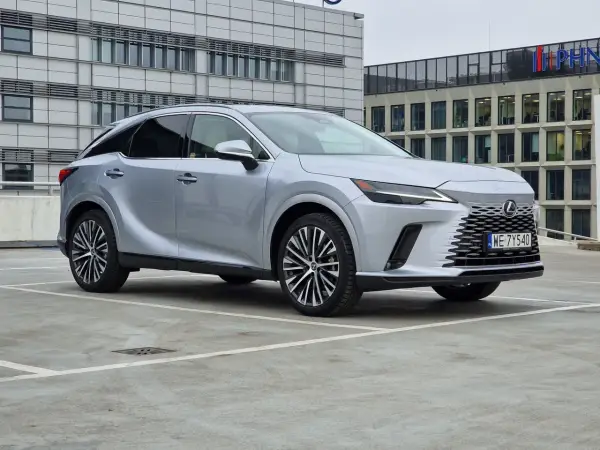 Srebrny Lexus RX 350h zaparkowany przed nowoczesnym budynkiem biurowym.