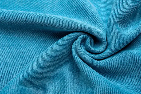 Textura de tela Tencel azul vibrante, suave y con caída, que evoca la comodidad y sostenibilidad de este tejido.