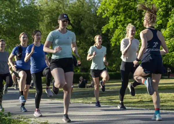 En grupp kvinnor tränar löpning i en park, redo att springa 3 km.