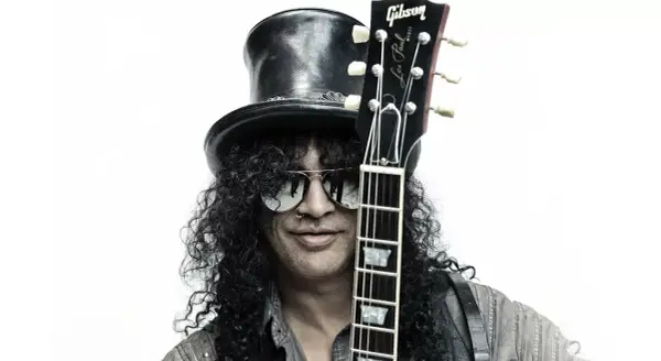 Le guitariste Slash, avec son chapeau haut-de-forme et ses lunettes de soleil, pose avec sa guitare Gibson Les Paul.