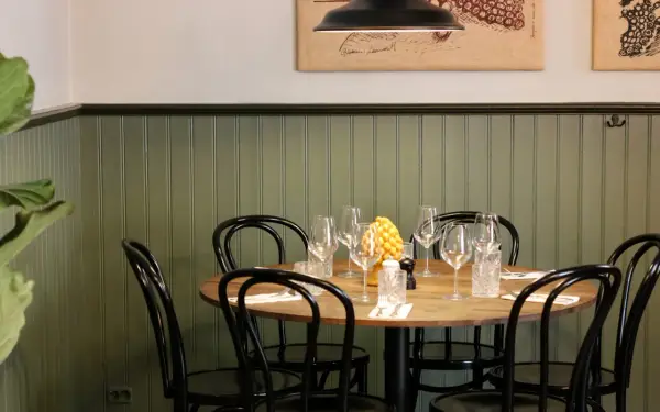 Ett runt bord med dukning för middag, med vinglas och en gul dekoration. En inbjudande atmosfär på la bottega del gusto.