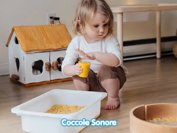 Bambina di 2 anni gioca con pasta in un vassoio, un'attività sensoriale divertente.