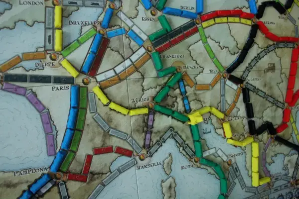 Planszowa mapa Europy z kolorowymi wagonikami. Która trasa jest najlepsza, by wsiąść do pociągu i odkryć nowe miasta?