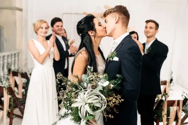 Brautpaar küsst sich, Gäste applaudieren. Der Beginn der standesamtlichen hochzeit ablauf ist ein emotionaler Moment.