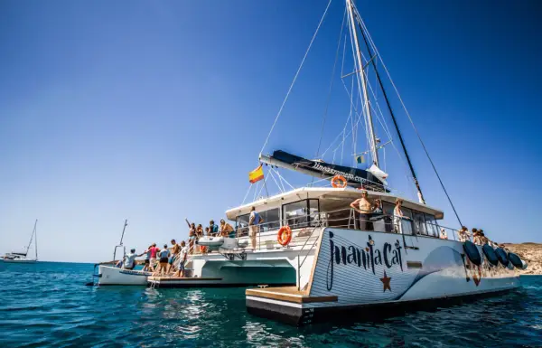 Catamarán "Juanita Cat" listo para el ferry Lanzarote La Graciosa. Turistas disfrutan del sol y el mar azul.
