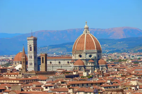 Vue panoramique de Florence avec le **dôme de Brunelleschi** dominant la ville, sous un ciel bleu clair.
