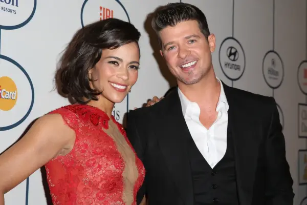 Paula Patton w czerwonej sukni i Robin Thicke na gali. Paula Patton znana z wielu filmów, uśmiecha się do aparatu.