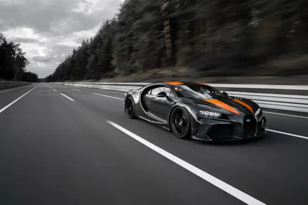 Czarny Bugatti Chiron Super Sport z pomarańczowymi pasami pędzi po pustej autostradzie.