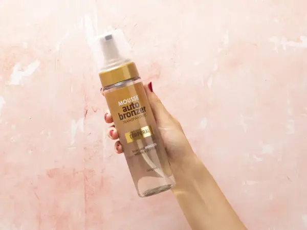 Mano sostiene botella de mousse autobronceador Deliplus de Mercadona. Bronceado natural y uniforme.