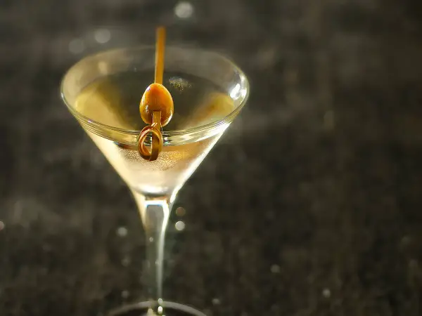Un verre à martini rempli d'un cocktail clair, garni d'une olive sur un cure-dent. Une image parfaite pour une vodka martini recette.