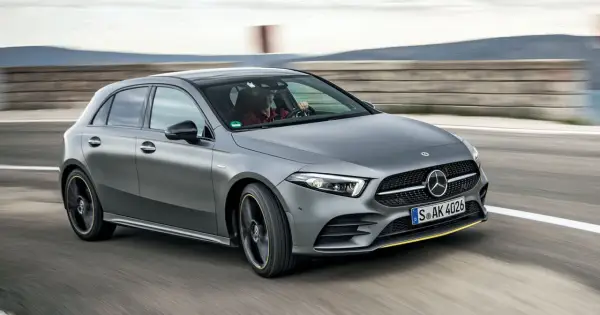Szary Mercedes W177 pędzi po torze, kierowca w czerwonej koszuli pewnie trzyma kierownicę.