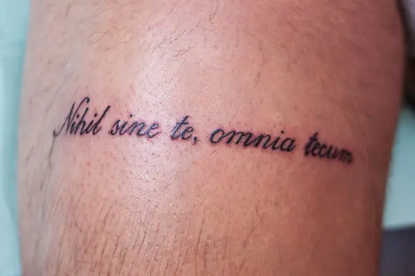 Tatuaż z łacińską sentencją "Nihil sine te, omnia tecum" na skórze.