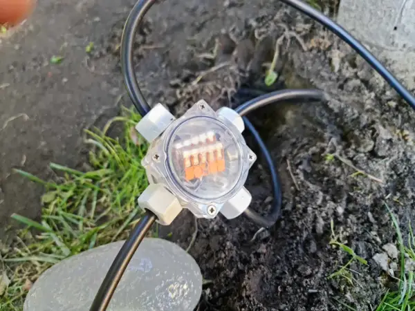 Przezroczysta puszka elektryczna do ziemi z pomarańczowymi diodami LED, podłączona do kabla.