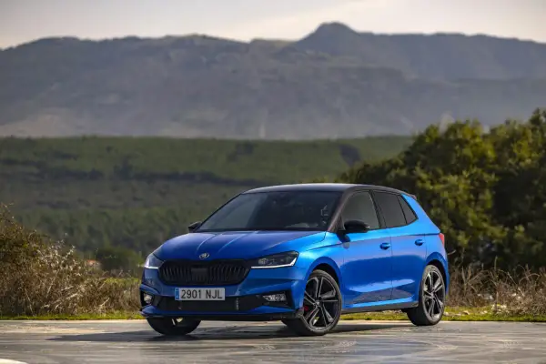 Un Skoda Fabia 130 azul brillante, con techo negro, aparcado en un paisaje montañoso.