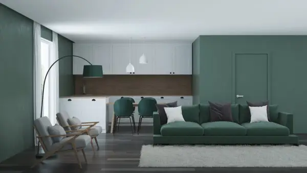 Nowoczesny salon z kuchnią, gdzie króluje **zielony kolor ścian**. Wygodna kanapa, fotele i krzesła tworzą przytulną przestrzeń.