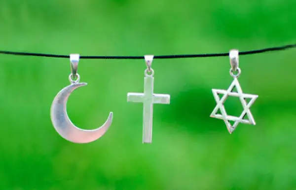 Srebrny półksiężyc, krzyż i gwiazda Dawida wiszą obok siebie. Symbolika islamu, chrześcijaństwa i judaizmu w harmonii.