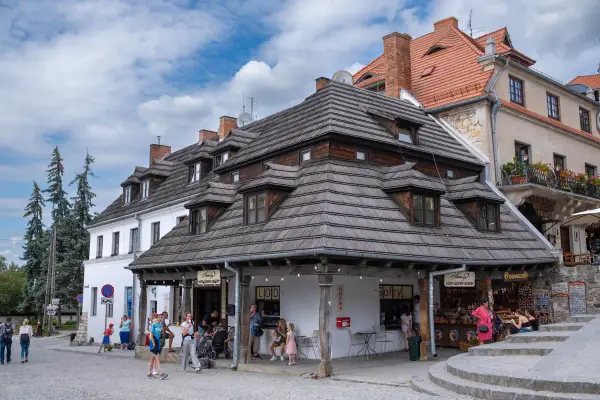 Tętniący życiem rynek w Kazimierzu Dolnym. Ludzie spacerują, kupują lody i gofry, podziwiając zabytkową architekturę.