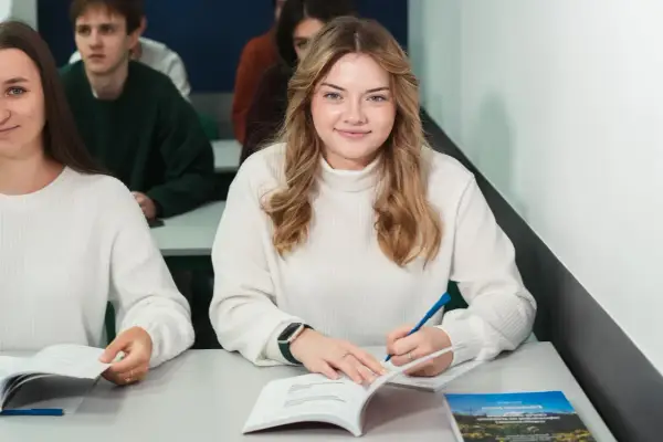 Uśmiechnięta studentka pisze w zeszycie, idealne zdjęcie do legitymacji.