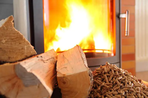 Bûches et granulés de bois près d'un poêle à granules en feu. Chaleur réconfortante pour l'hiver.