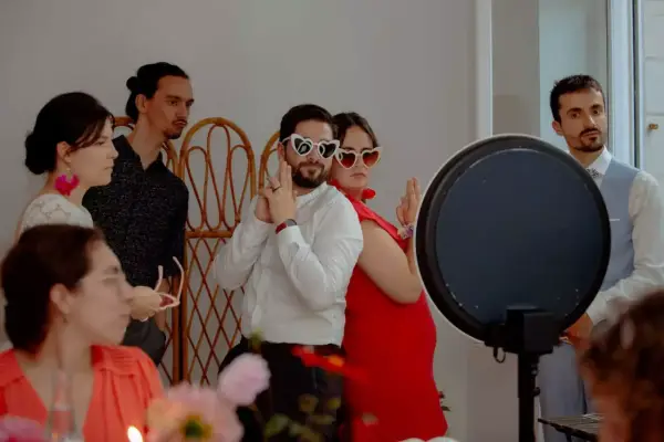 Des invités s'amusent avec des lunettes en forme de cœur lors d'un repas enfant mariage.
