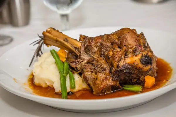 Une souris d'agneau braisée, servie avec une purée onctueuse, des haricots verts croquants et des dés de carottes, le tout nappé d'une sauce savoureuse.