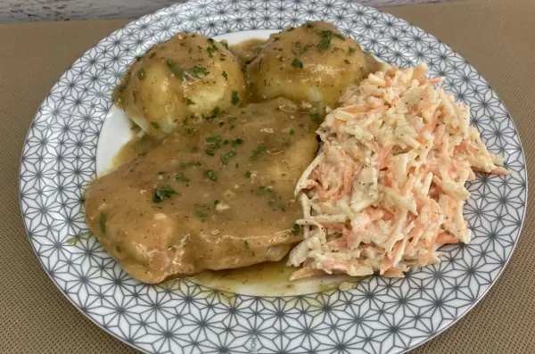 Pyszna pierś z kurczaka w sosie własnym, podana z purée ziemniaczanym i surówką z marchewki i kapusty.