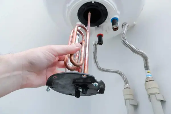 Mano retirando resistencia de cobre para saber como limpiar un termo por dentro.