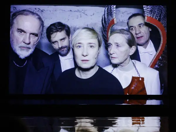 Kazimierz, reżyser i aktor teatralny, w otoczeniu aktorów na scenie.