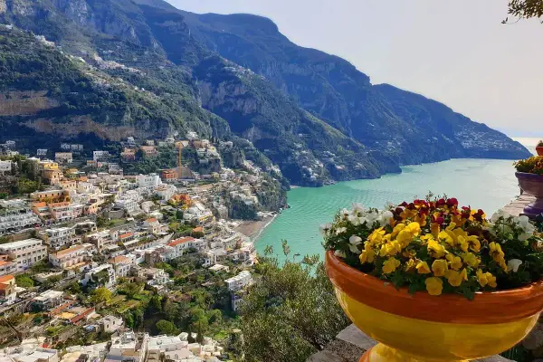 Colorful flowers bloom overlooking Positano, a stunning town cascading down the cliffs. This view offers inspiration for where to stay in Amalfi Coast.