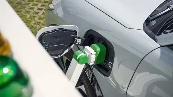 Zielony kabel ładowarki podłączony do portu ładowania samochodu elektrycznego.