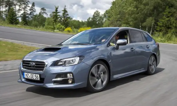 Szary Subaru Levorg na zakręcie drogi, otoczony zielenią.