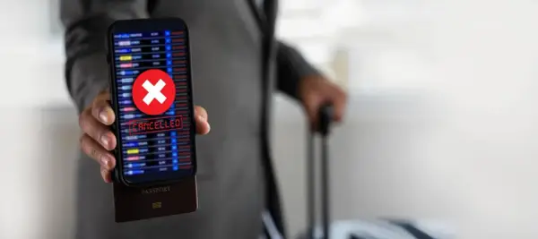 Telefon z napisem "CANCELLED" i czerwonym krzyżykiem, pod nim paszport. Podróż z Ryanair zwrot biletu stał się niemożliwy.