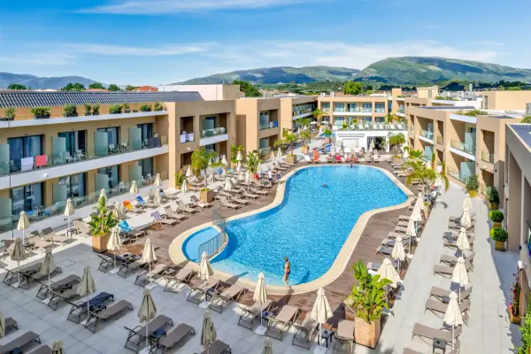 Luksusowy hotel White Olive Elite w Laganas, Grecja. Basen, leżaki i palmy tworzą idealne miejsce na relaks.