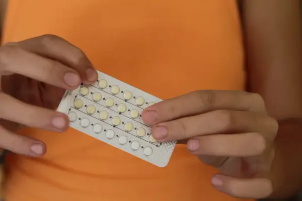 Manos sostienen un blíster de pastillas anticonceptivas. Me he quitado el anillo y no me baja la regla, ¿será por esto?