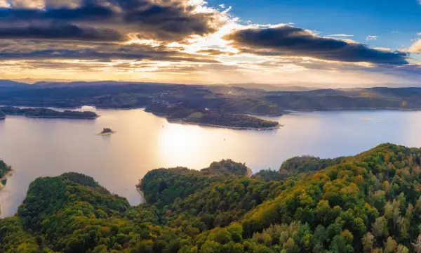 Zachód słońca nad jeziorem Solina. Widać zalesione wzgórza, wyspy i zatoczki. Idealne miejsce na odkrywanie atrakcji Solina i okolice.