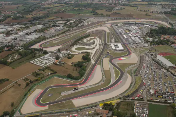 Vista aerea del circuito di Misano, noto anche come circuito San Marino, con tribune piene di spettatori e un vasto parcheggio.
