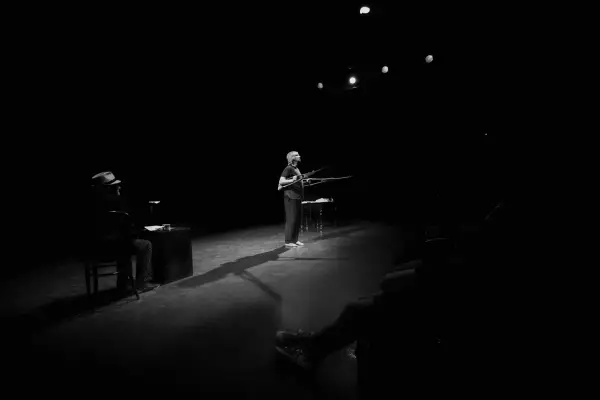 Na scenie Teatru Rondo w Słupsku kobieta z karabinami, mężczyzna w kapeluszu siedzi przy biurku.