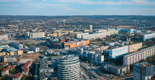 Widok na Rzeszów z lotu ptaka. Widać nowoczesne budynki, centrum handlowe i osiedla mieszkaniowe. Ceny mieszkań Rzeszów są tu widoczne w kontekście rozwoju miasta.