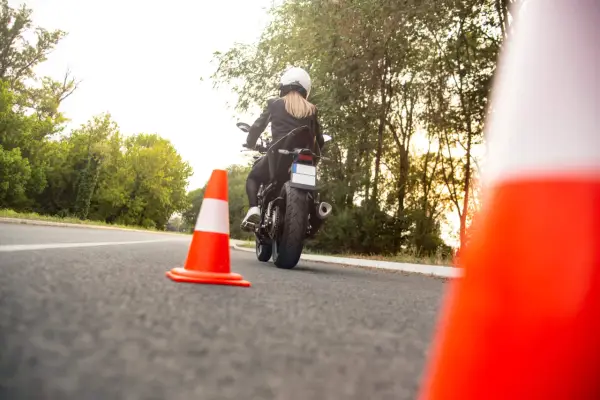 Kobieta na motocyklu podczas egzaminu na prawo jazdy kat A. Sprawdza cenę kursu.