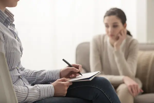 Psycholog notuje podczas sesji. Zastanawiasz się, ile zarabia psycholog prywatnie? To zależy od wielu czynników.