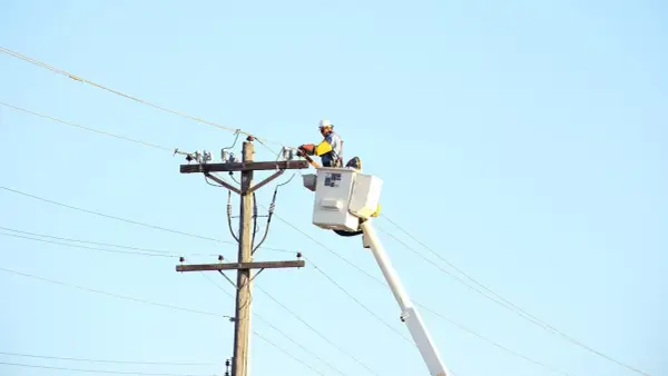 Elektryk wysokich napięć w podnośniku pracuje przy linii energetycznej.