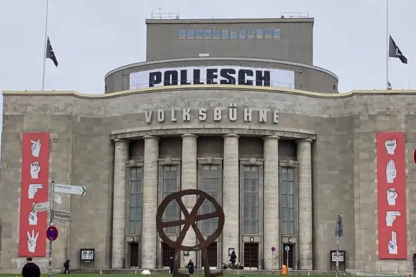 Volksbühne Berlin mit Banner "POLLENSCH". Annegret Hahn könnte hier eine Aufführung besuchen. Rote Banner mit Gebärdensprache.