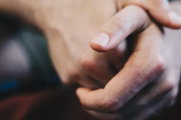 Dita intrecciate, un primo piano che evoca il senso di vibrazione interna e le sue cause, forse ansia o attesa.