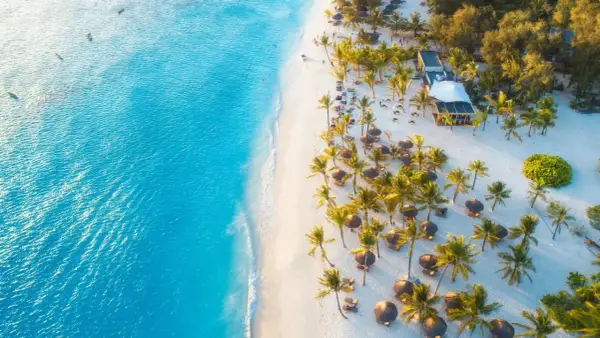 Rajska plaża na Zanzibarze z turkusową wodą, białym piaskiem, palmami i luksusowym resortem. Idealne miejsce, kiedy na Zanzibar.
