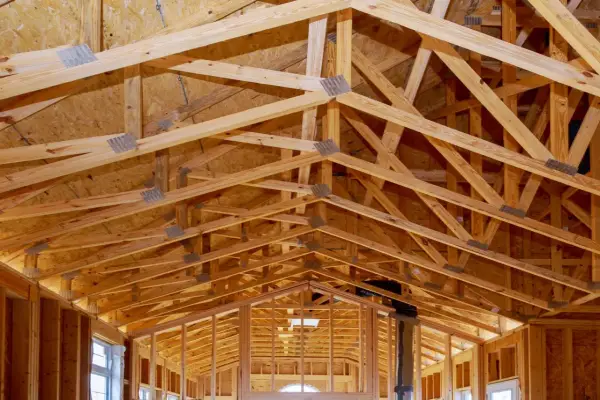 Structure complexe de charpente en bois, avec des fermes et des poutres formant un contreventement bois solide pour une nouvelle construction.
