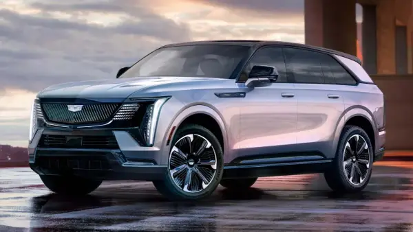 Elegancki Cadillac Escalade 2025 w kolorze srebrnym, z czarnym dachem i stylowymi felgami, prezentuje się imponująco na mokrej nawierzchni.