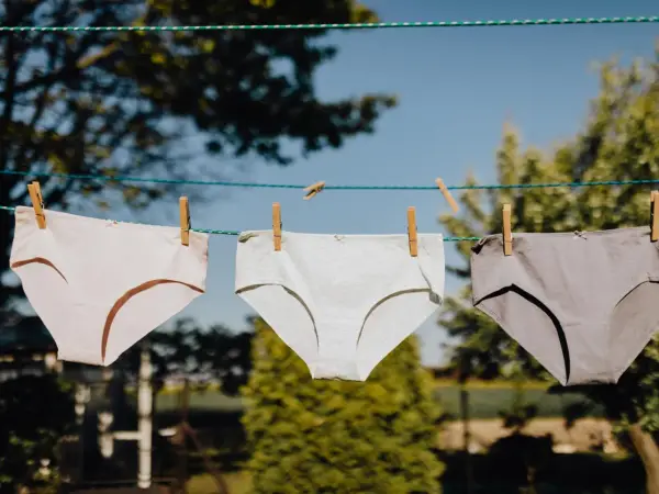 Drei Unterhosen in verschiedenen Grautönen trocknen an einer Wäscheleine. Ein Zeichen für frische Wäsche nach dem unterhosen waschen.