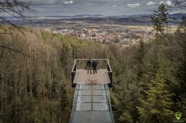 Dwie osoby stoją na szklanym tarasie widokowym, podziwiając panoramę Starego Sącza. To jedna z głównych atrakcji turystycznych regionu.