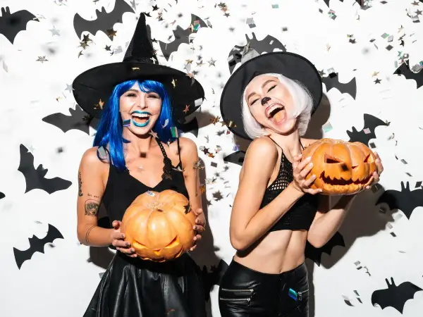 Dwie kobiety w strojach czarownic trzymają dynie. Świetne inspiracje na Halloween!